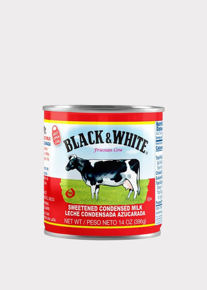 A 14 oz can of Black & White Sweetened Condensed Milk on a plain white background. The can features the classic Black & White brand logo, a picture of a black and white cow on a green field, and red and white packaging.