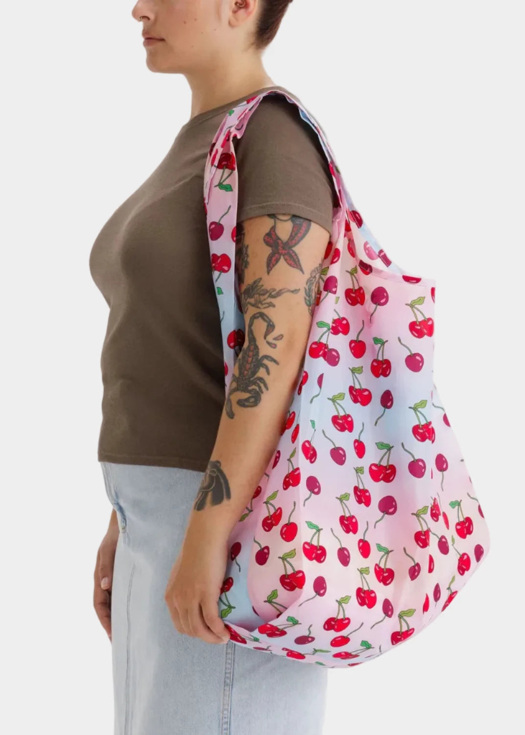 Person holding a cherry-patterned reusable bag against a white background
