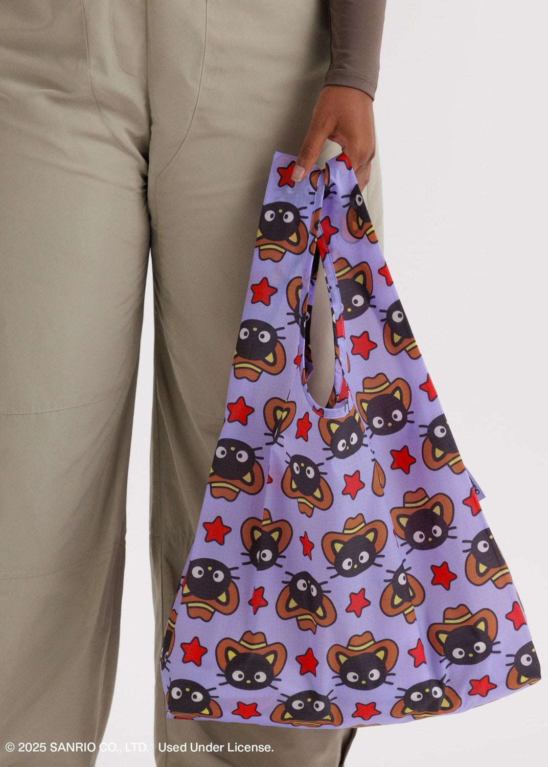 Person holding a purple bag with cartoon character pattern on a plain background