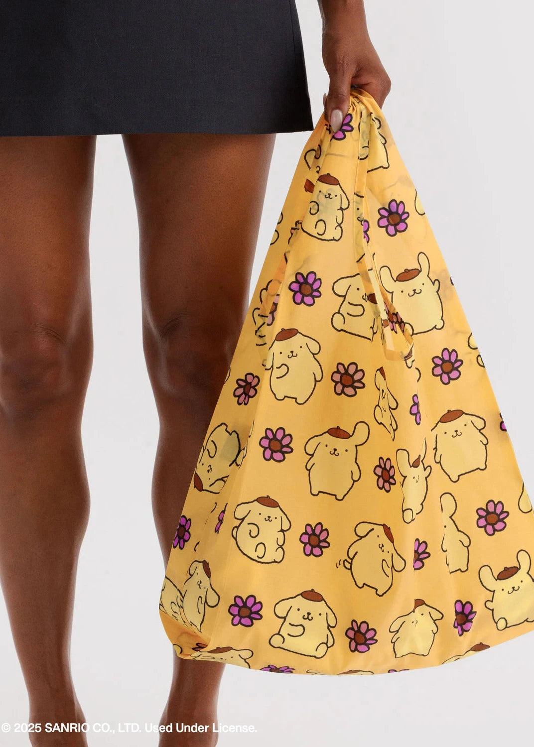 Person holding a yellow drawstring bag with cartoon character pattern on a white background