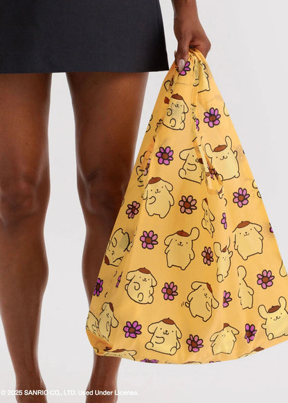 Person holding a yellow drawstring bag with cartoon character pattern on a white background