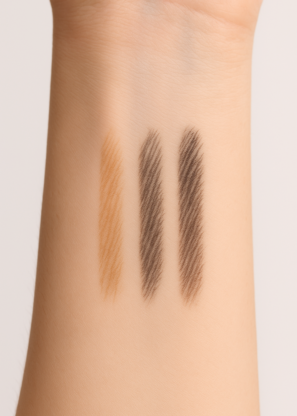 Brow pencil swatches on a person's arm with two different shades.