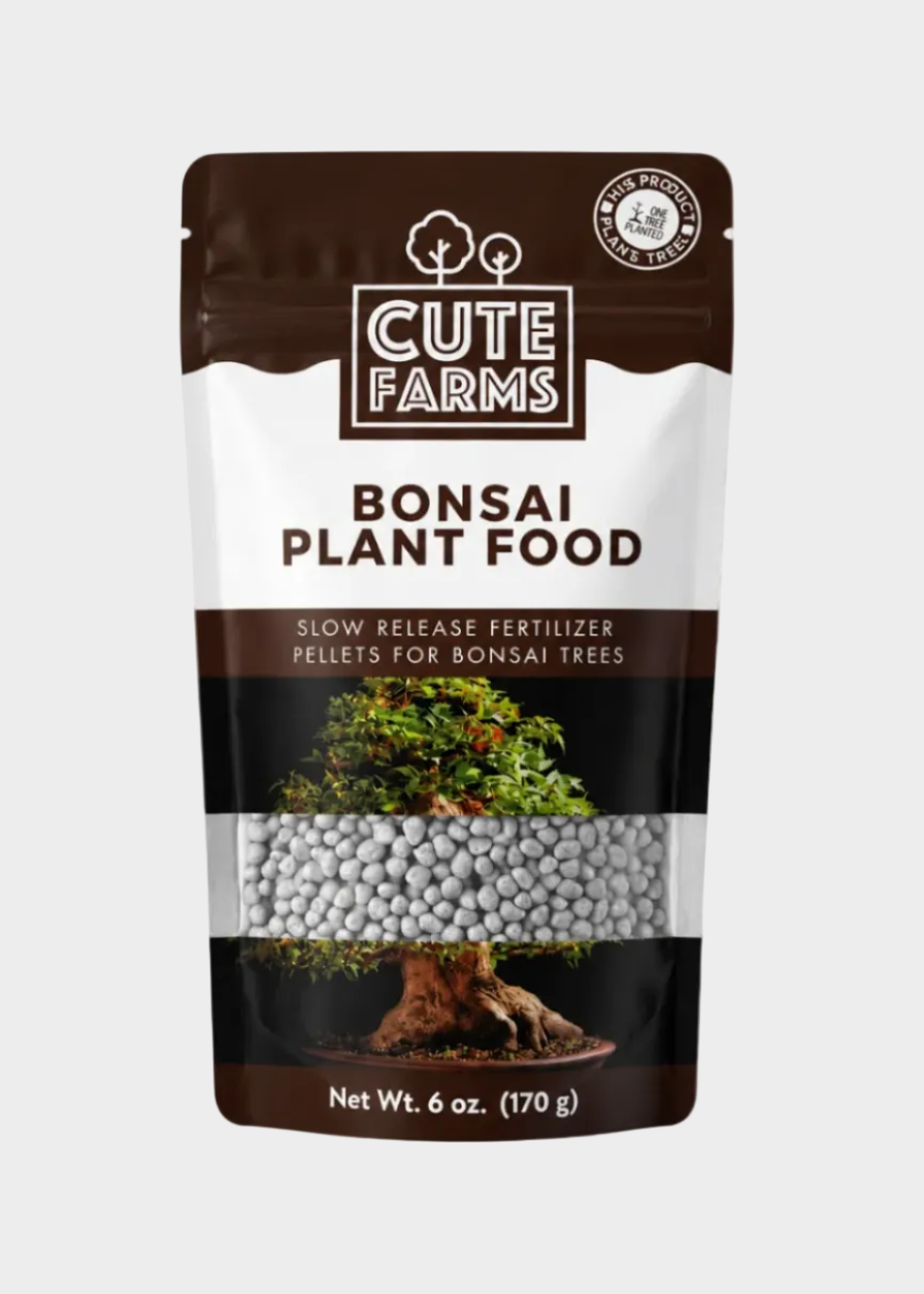 A 6 oz stand-up pouch of Cute Farms Bonsai Plant Food slow-release fertilizer pellets, shown next to a potted bonsai tree on a clean white background.