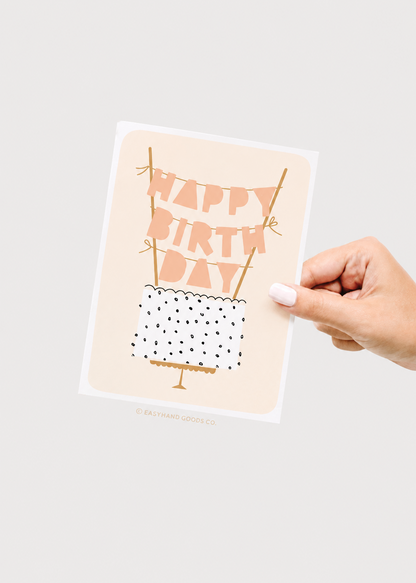 Hand holding a birthday card with 'Happy Birthday' text on a plain background