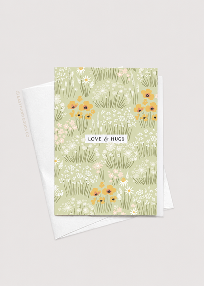 Greeting card with floral design and 'Love & Hugs' text on a light gray background