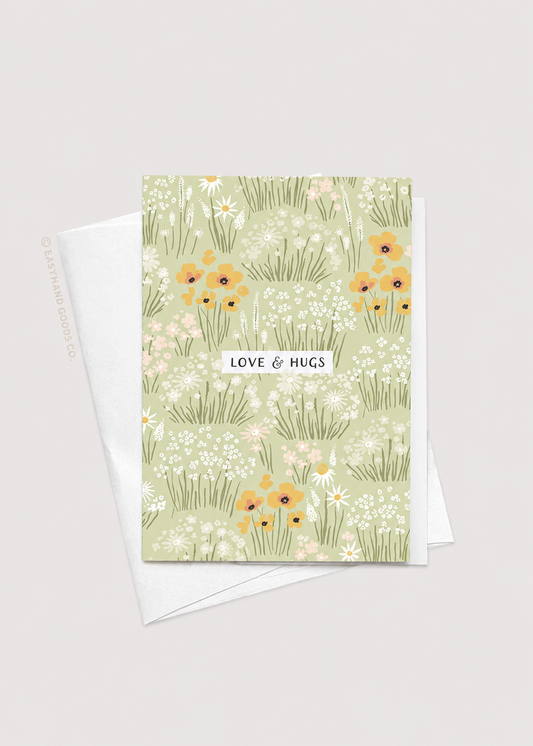 Greeting card with floral design and 'Love & Hugs' text on a light gray background