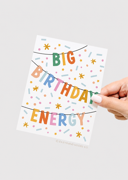 Hand holding a card with 'BIG BIRTHDAY ENERGY' text on a white background