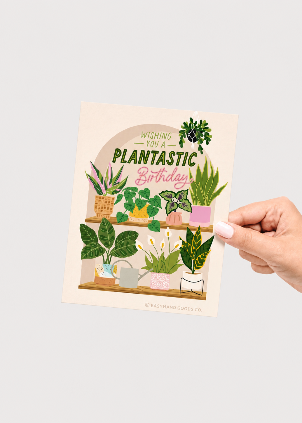 Hand holding a card with plant illustrations and text on a light gray background