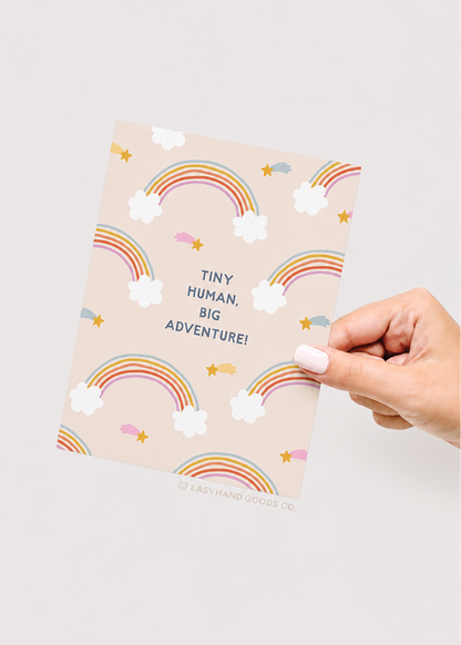 Greeting card with rainbow and cloud pattern held by a hand on a light background