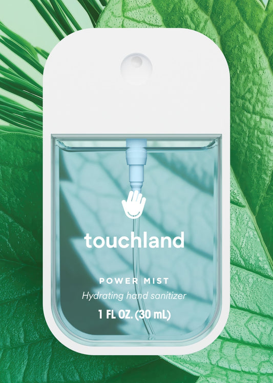 Touchland power mist hand sanitizer packaging on a green leaf background