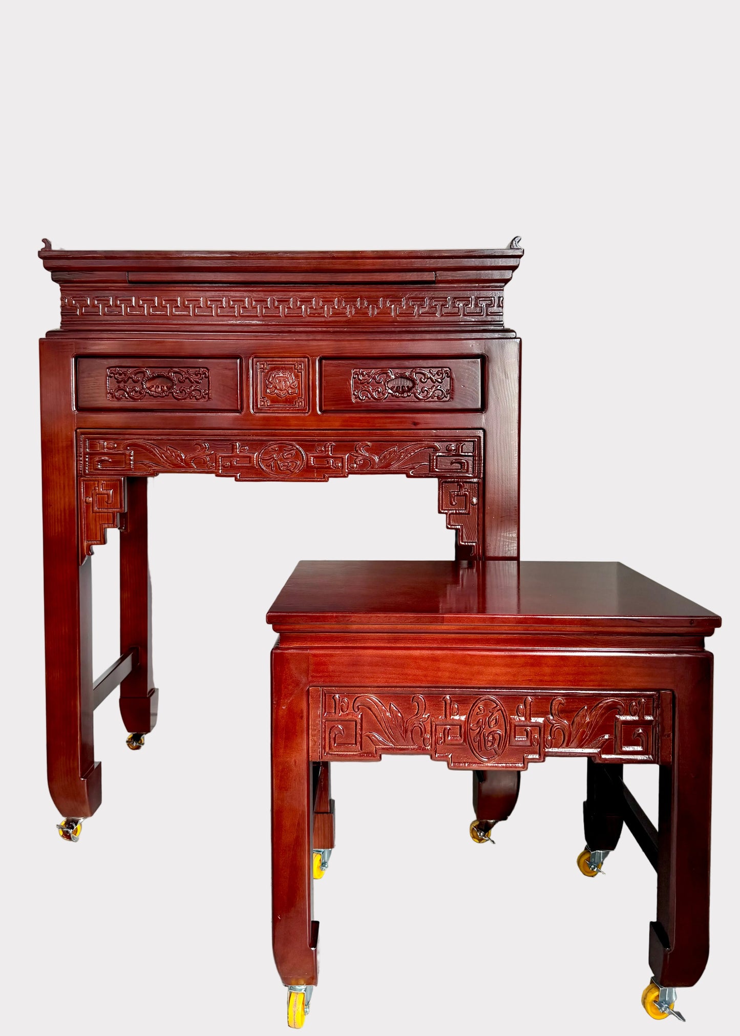 A dark reddish-brown carved wooden writing desk and matching stool set on casters, photographed indoors against a plain light wall and speckled gray floor.