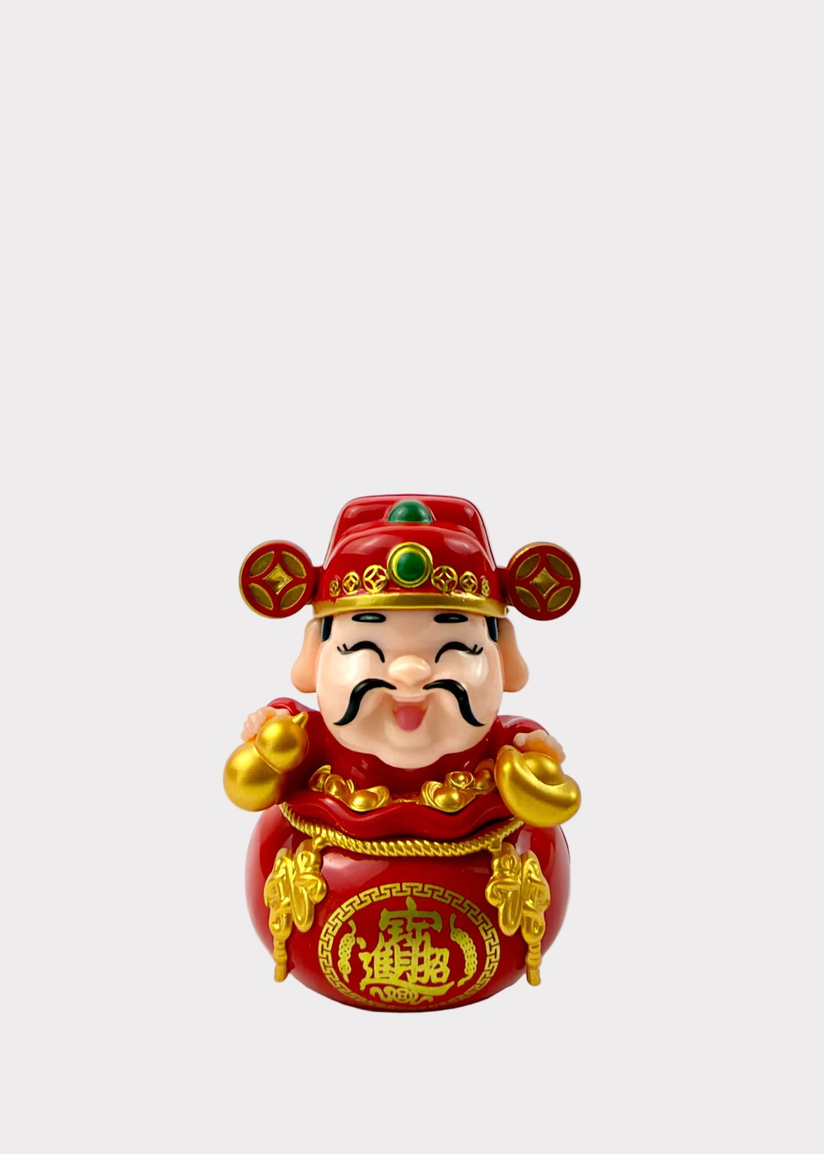 A Chinese Lucky Feng Shui figurine of a smiling man in a red robe and hat with gold accents, standing on a white surface against a white wall solar toy.
