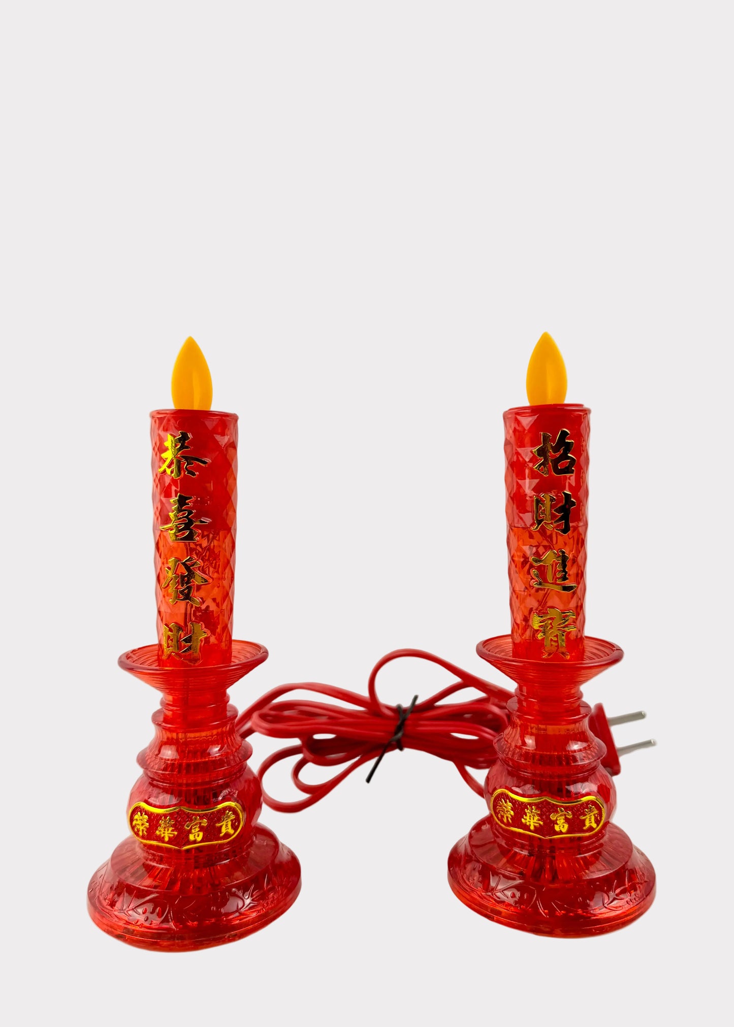 A pair of red plastic electric prayer candles with yellow flame tips and gold Chinese characters, shown on a white surface with a white background.