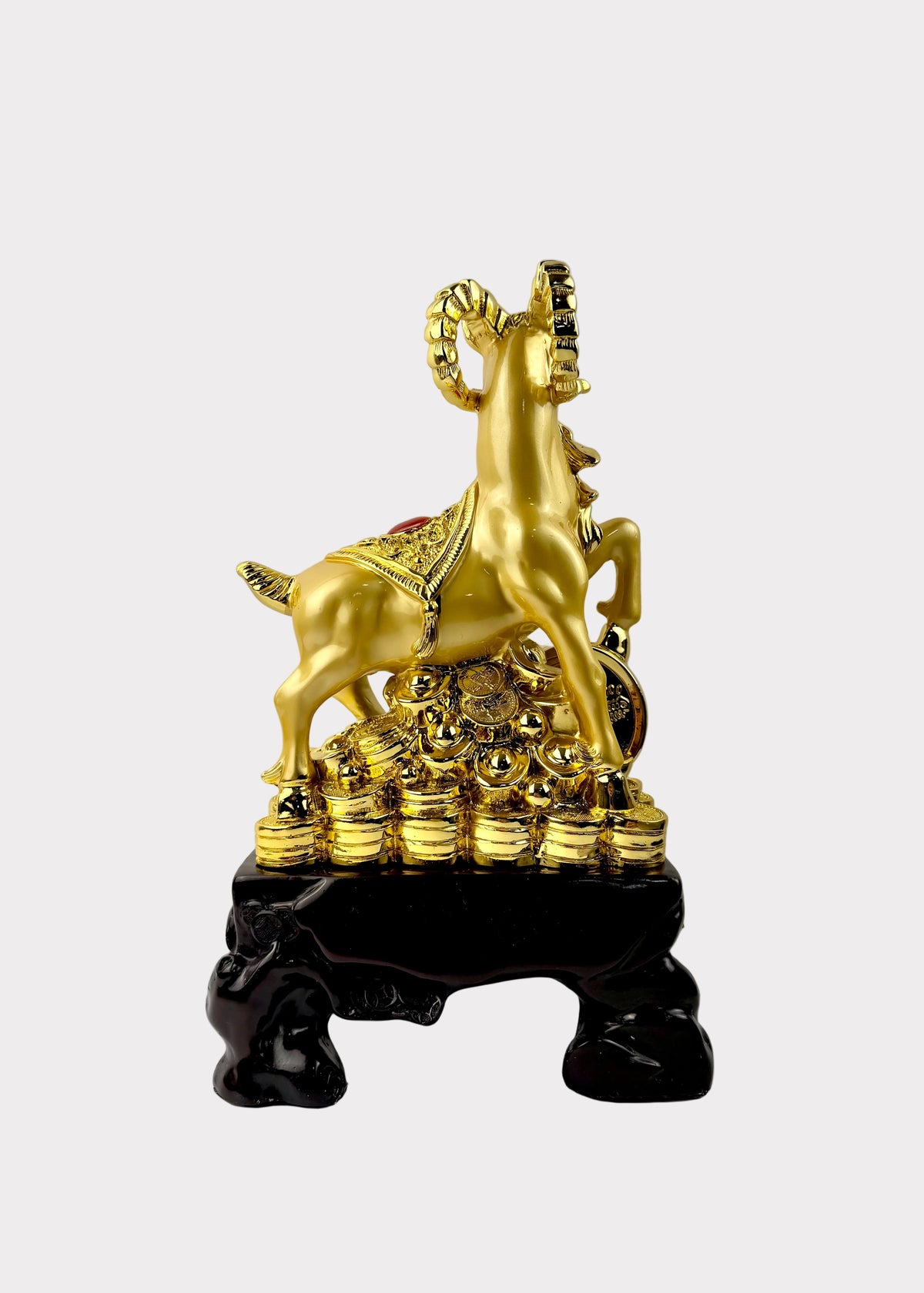 A golden ram figurine standing on a pile of gold coins, mounted on a glossy black base, photographed against a light gray background.