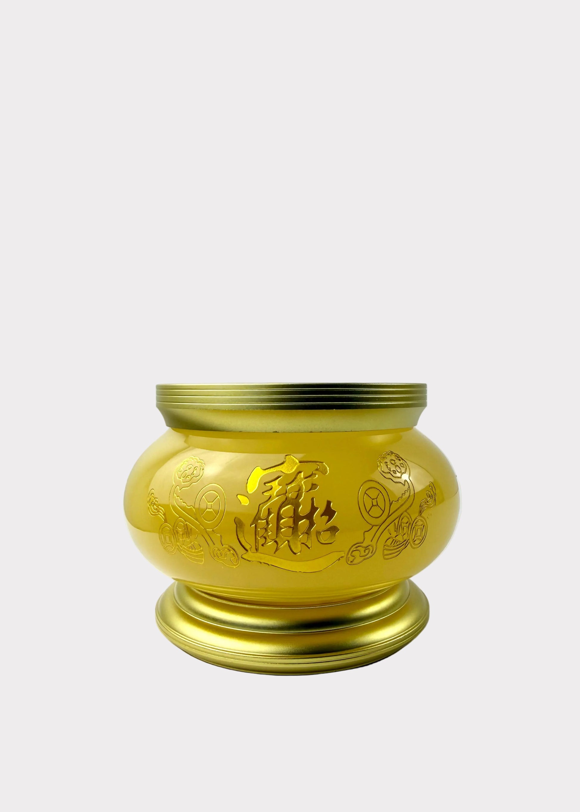 A shiny gold-colored metal incense burner with engraved Chinese characters and floral patterns, sitting on a white surface against a white wall.