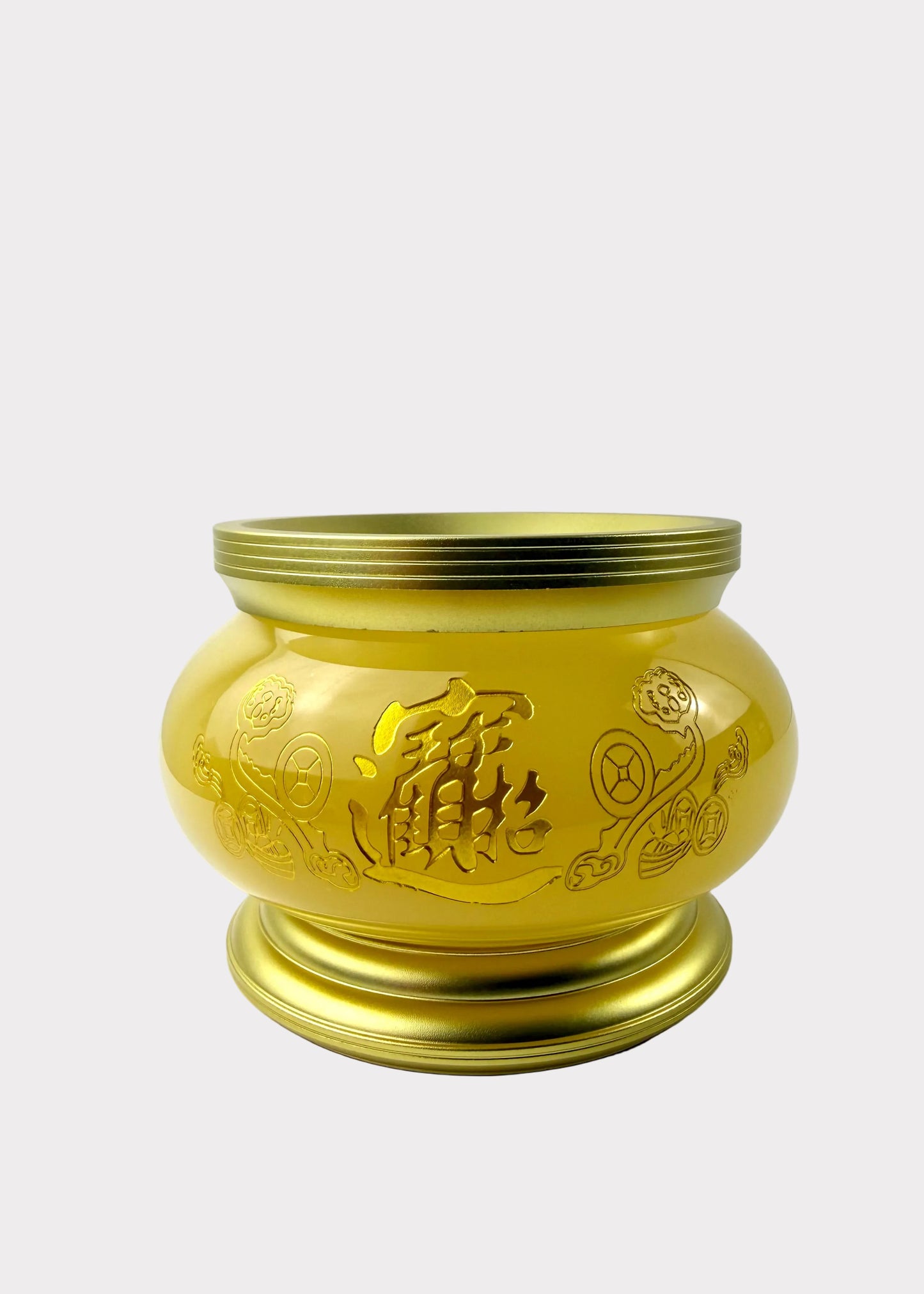 A shiny gold-colored metal incense burner with engraved Chinese characters and floral patterns, sitting on a white surface against a white wall.