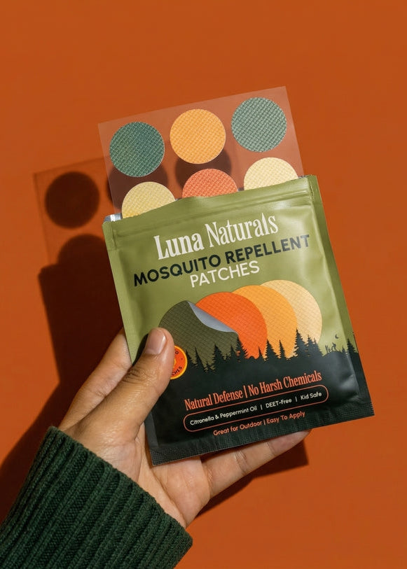 Hand holding a package of Luna Naturals mosquito repellent patches against an orange background