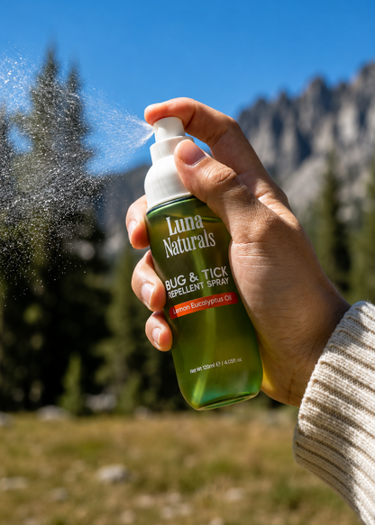 Hand holding Luna Naturals bug & tick repellent spray with mountains in the background