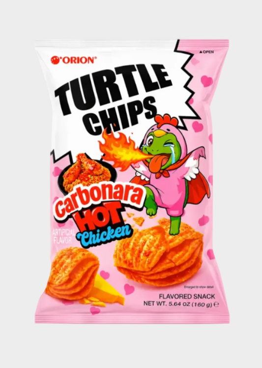 A bag of Orion Turtle Chips Carbonara Hot Chicken flavored snack chips on a light gray background. The packaging is primarily pink and white with cartoon graphics of a crying turtle in a pink cape and images of the orange-red chips.
