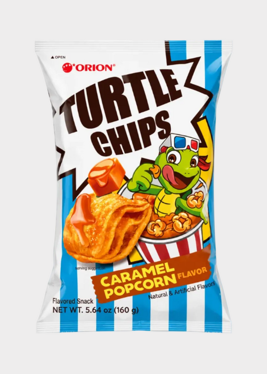 A bag of Orion Turtle Chips Caramel Popcorn Flavor snack chips, featuring a white bag with blue side stripes, bold brown 'TURTLE CHIPS' text, a cartoon turtle character, and a large image of caramel-coated chips.