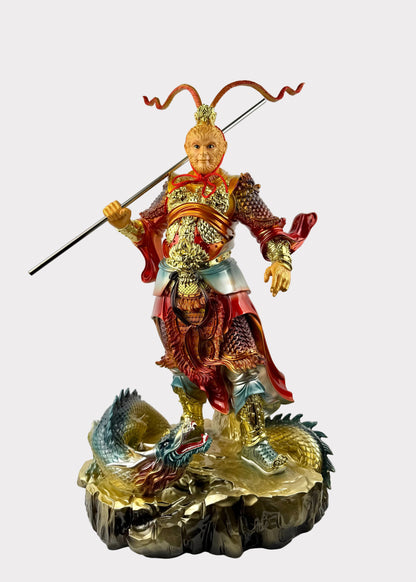 A highly detailed, multicolored statue of the Chinese deity Huang San (Monkey King) standing on a dragon base, holding a spear, photographed against a plain white wall.