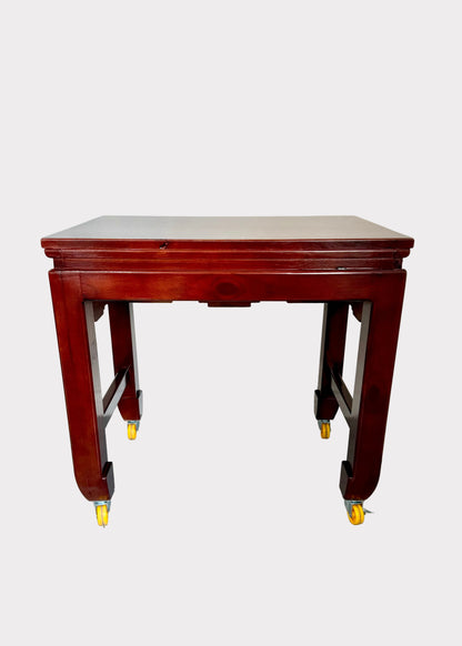 A reddish-brown wooden table with casters on the legs, shown against a plain light gray background.