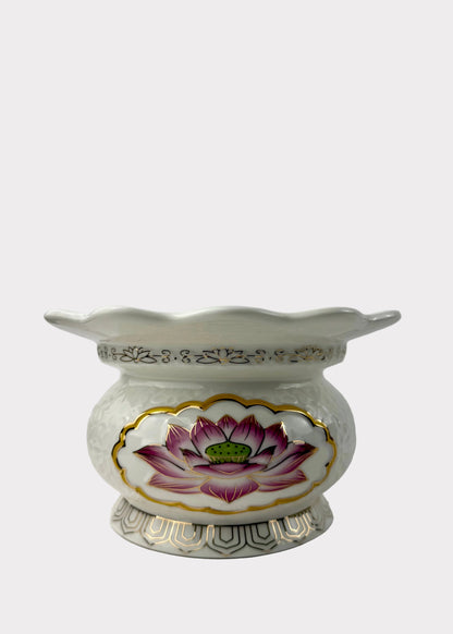 A white ceramic flower pot with a scalloped rim, featuring a hand-painted pink and purple lotus flower with a green center on the front, accented with gold trim.