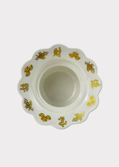 A white ceramic bowl with a scalloped rim, decorated with gold Chinese characters and floral motifs, set against a plain white background.