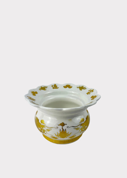 A white ceramic vase with a fluted rim and gold decorative patterns, set against a plain light gray background.