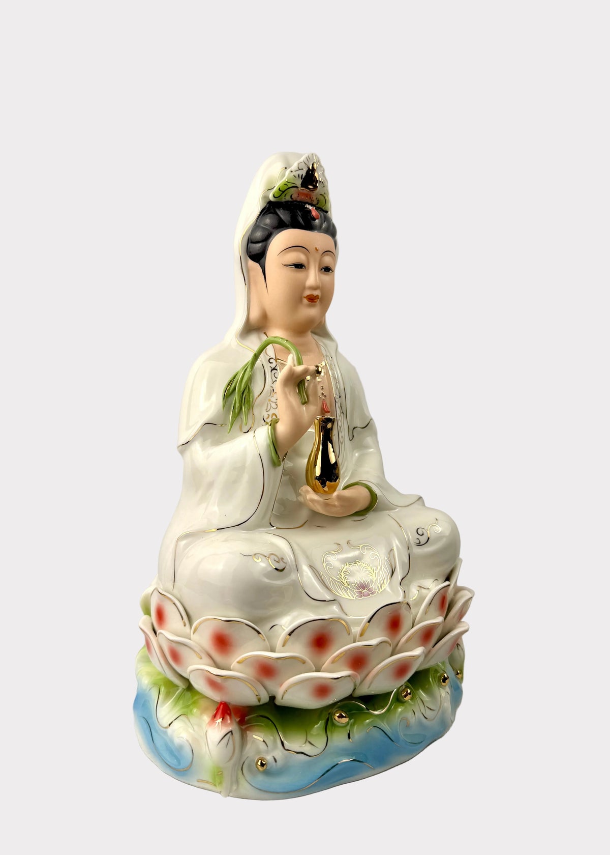 A ceramic figurine of Guanyin seated on a lotus base, featuring a white robe, black hair, and colorful painted details in green, red, and blue.