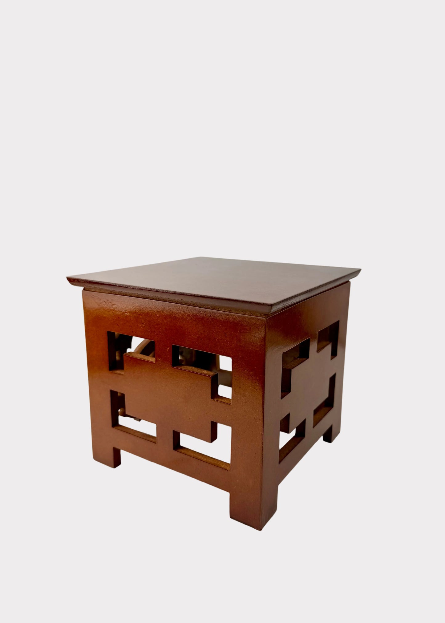 A small square wooden side table or stool with a glossy reddish-brown finish and geometric cutout details on the sides, photographed against a plain light background.
