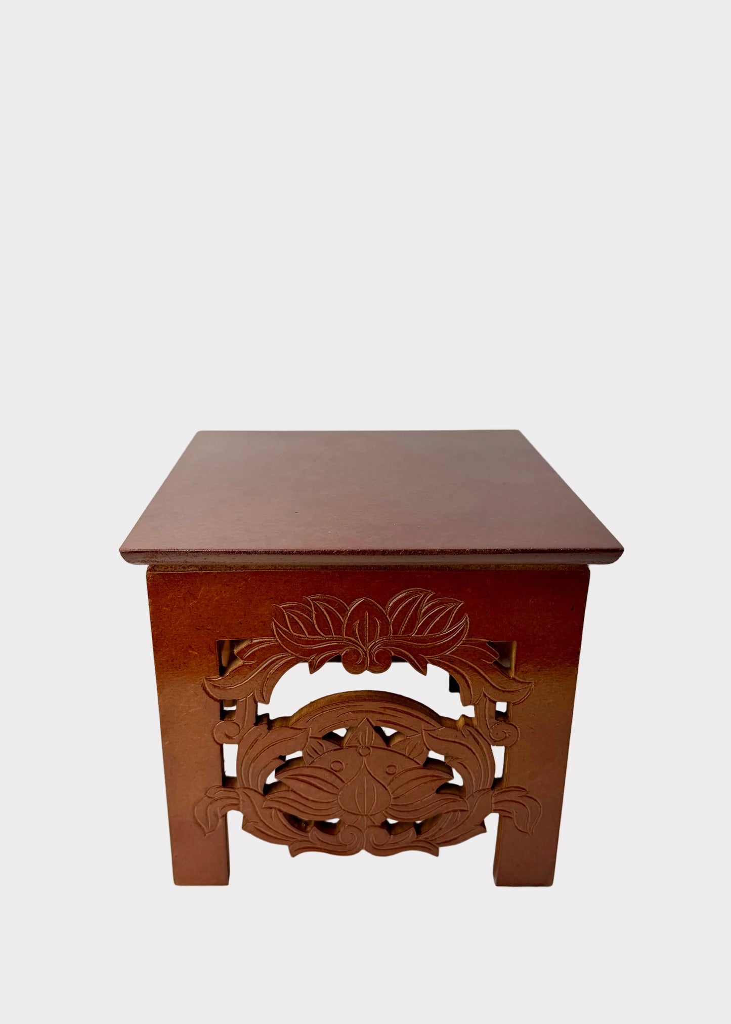 A small square wooden stool or side table with carved floral and scrollwork details on the front panel, shown against a plain light background.