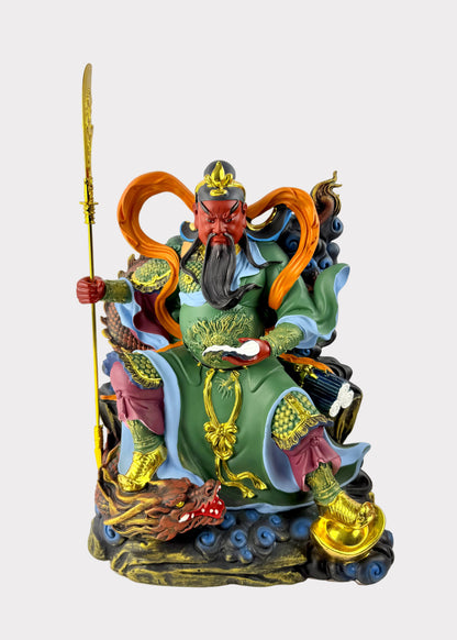 A colorful Chinese deity statue depicting a warrior seated on a cloud base, holding a golden staff, with green, gold, orange, red, and blue painted details.