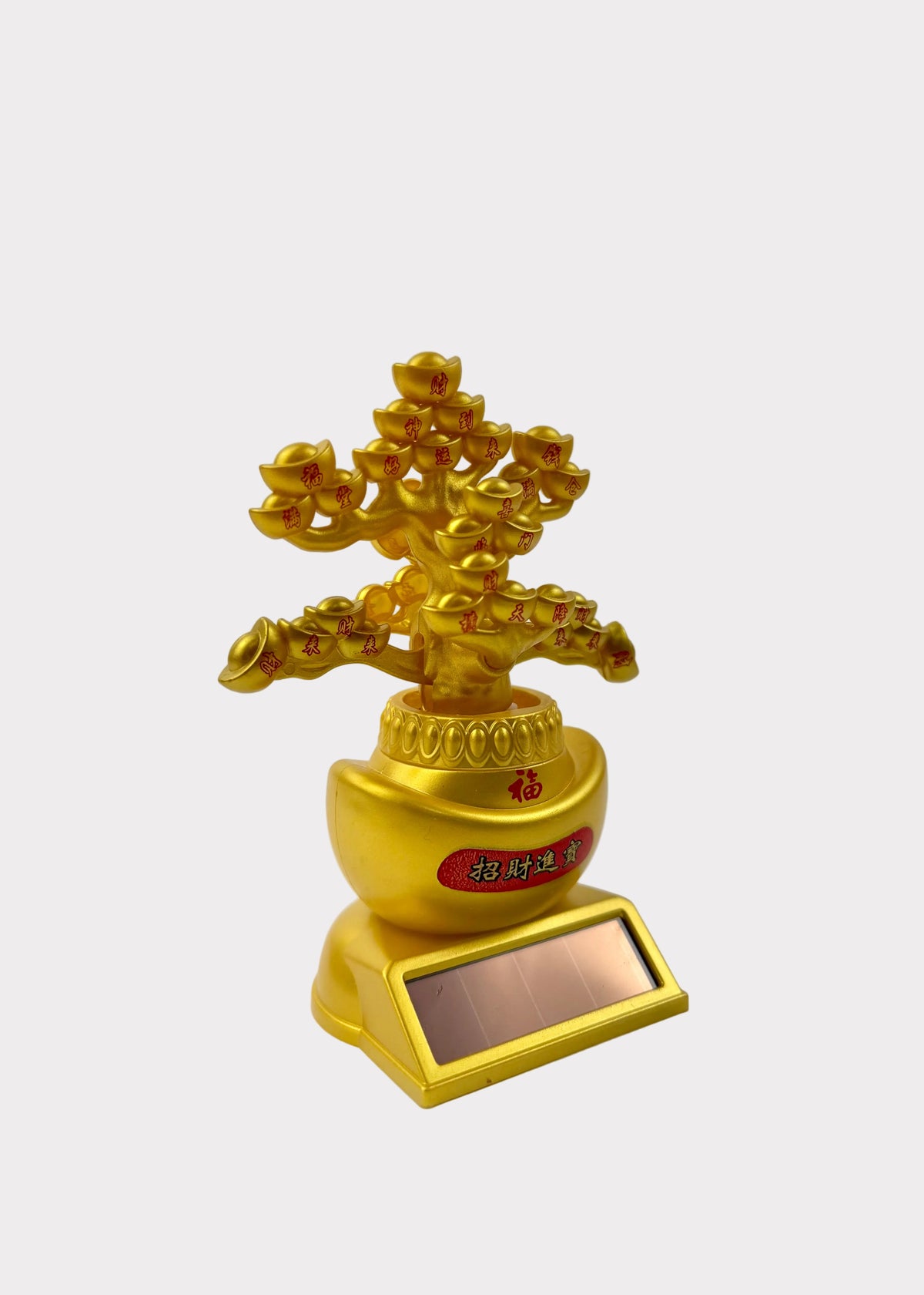 A golden decorative bonsai-style tree figurine with a small rectangular solar panel base, photographed against a plain light gray studio background.