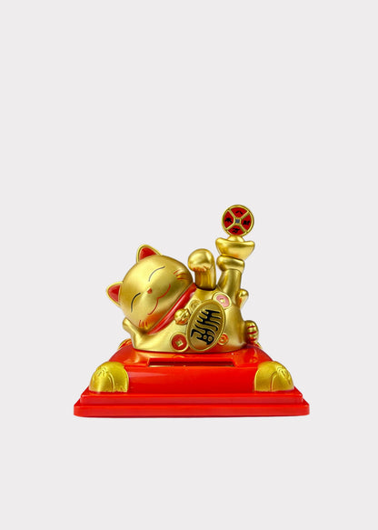 A golden lucky cat figurine with a raised paw holding a coin, resting on a red base with Chinese characters, set against a light gray background.
