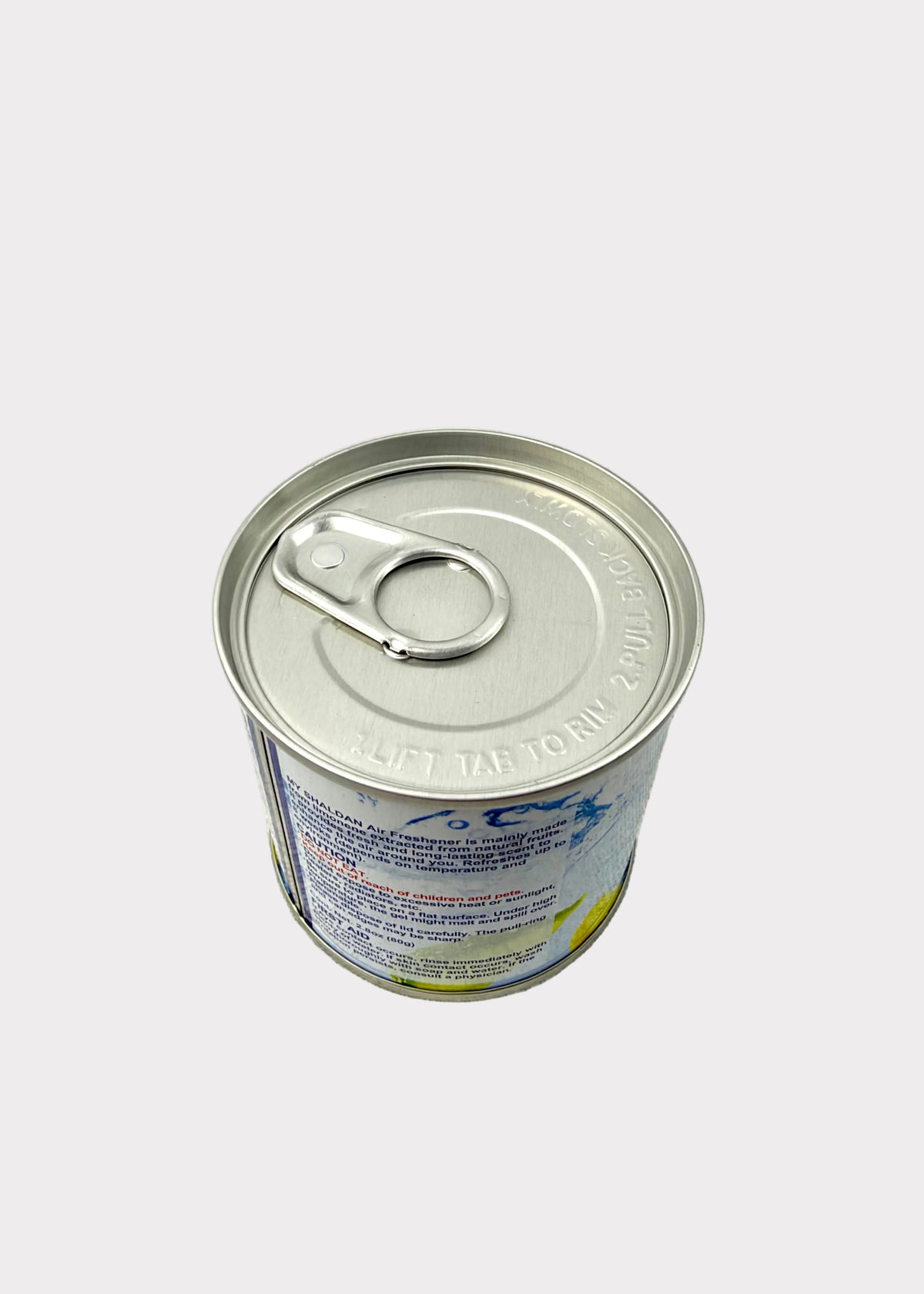 A silver metal can with a pull-tab lid, photographed from above on a light gray textured surface against a plain light background.