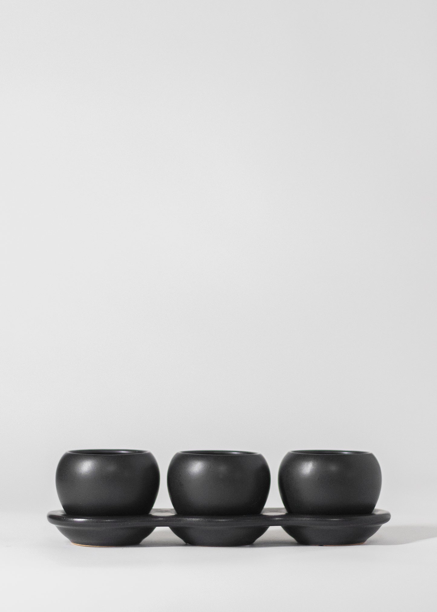 three planters on saucer in black. each planter has a 2" opening