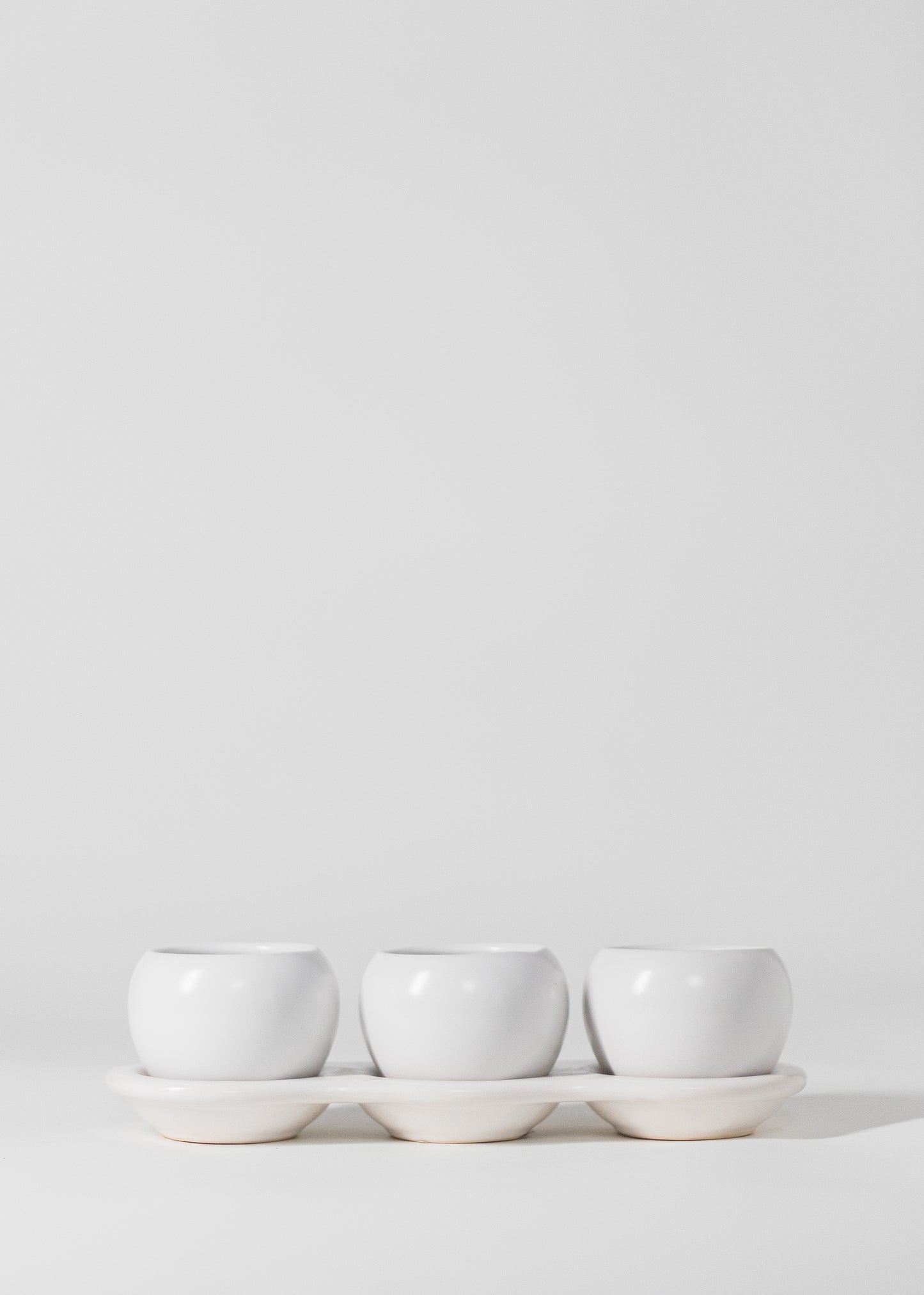 three planters on saucer in white. each planter has a 2" opening