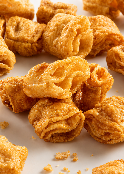 Golden-brown crispy fried snack pieces scattered on a white background.