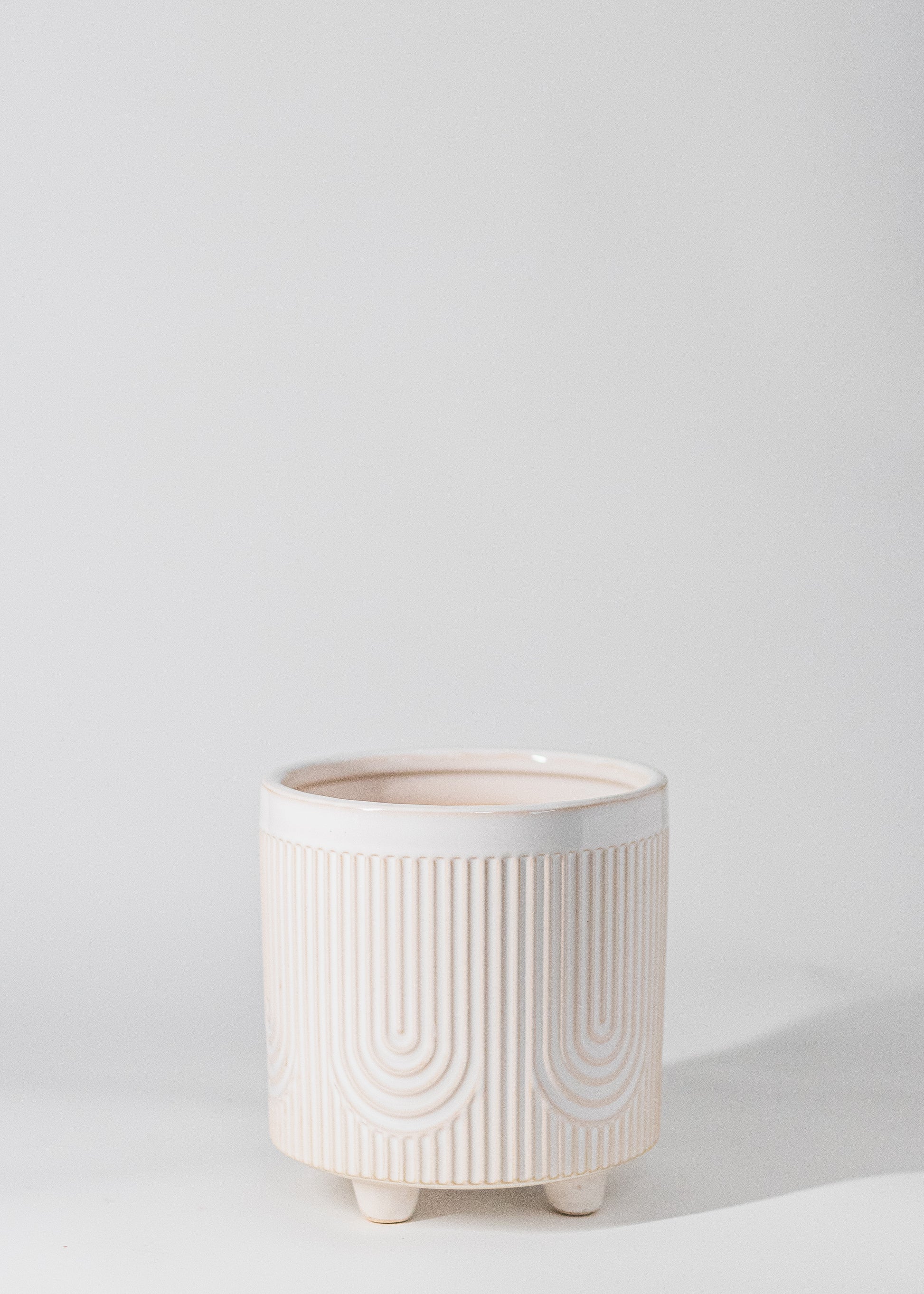 footed planter with U pattern embossed into white glazed ceramic