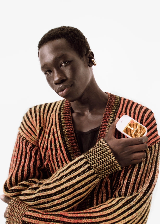 Person wearing a striped sweater holding a container of fries on a white background