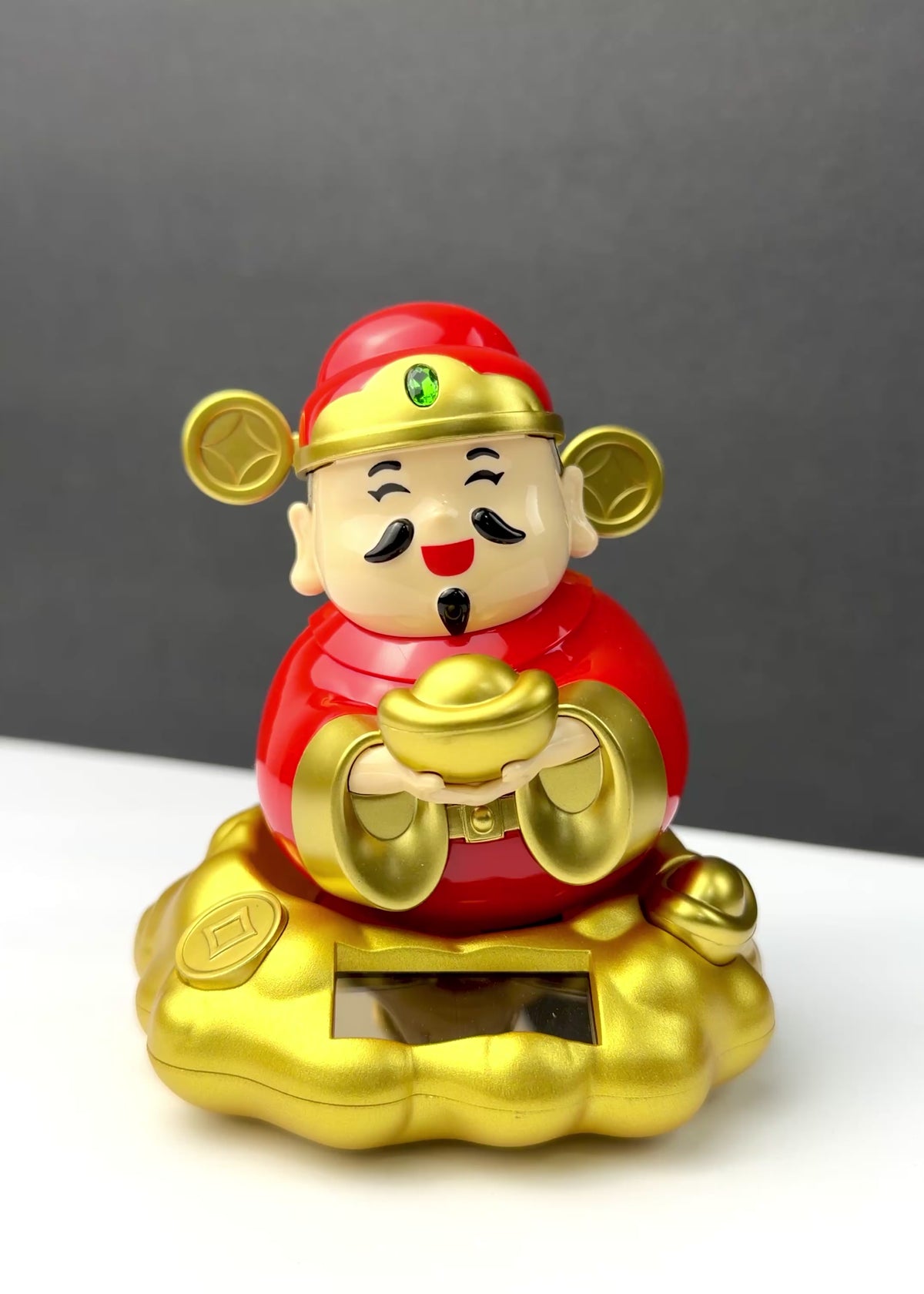 Solar powered rocking Chinese God of Wealth Cai Shen figurine in red and gold holding a gold ingot while sitting on a golden cloud base.